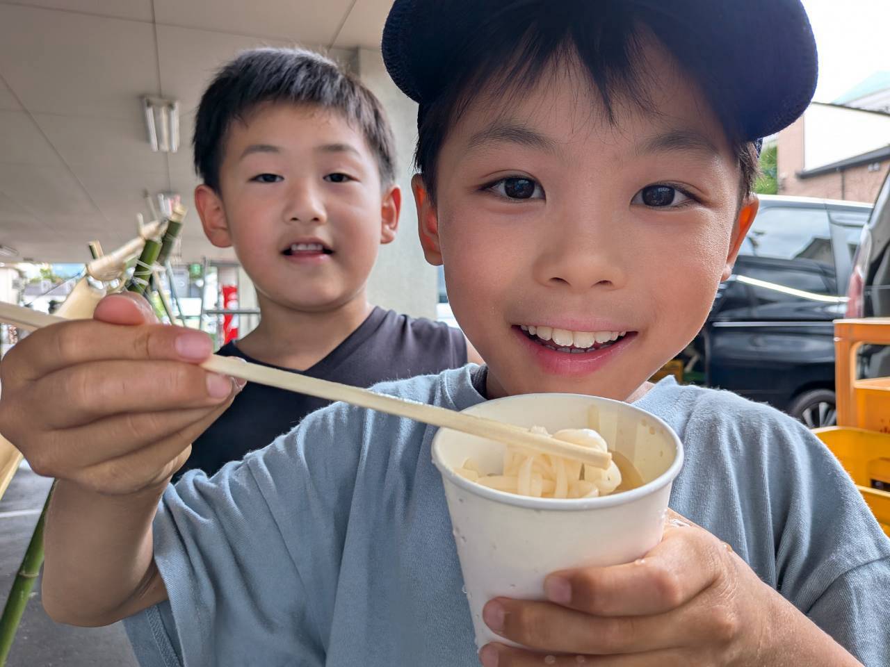そうめんを頬張り、笑顔を見せる男の子たち