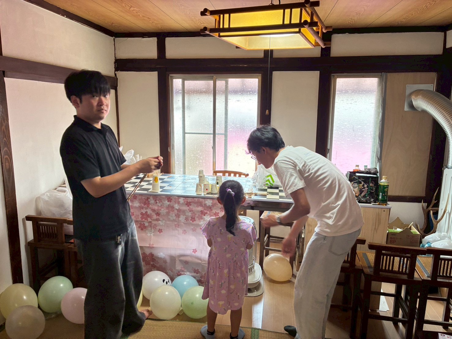 風船で飾られた二階の座敷で、準備をする学生たちと子ども
