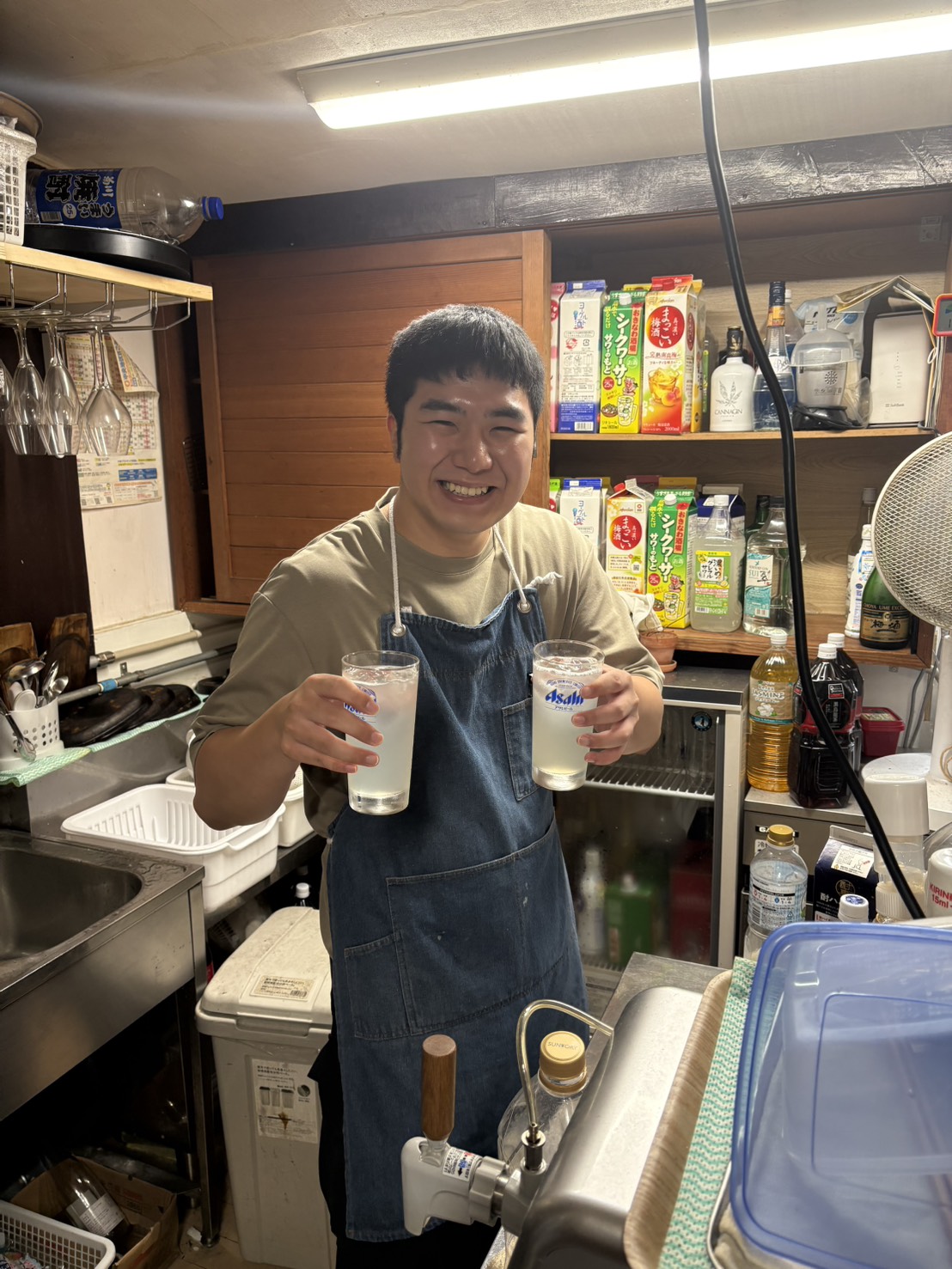 厨房でグラスを掲げ、笑顔で乾杯するスタッフ